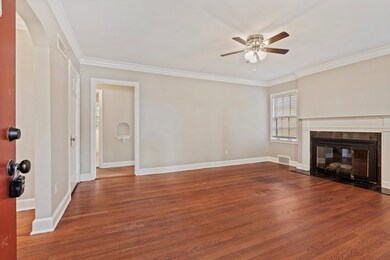 Unfurnished living room featuring ornamental molding, dark wood-style flooring, a fireplace with flush hearth, and a ceiling fan