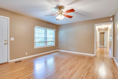 Large living room with ceiling fan and refinished hardwood flooring