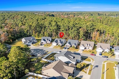 Aerial view of property and surrounding area featuring a heavily wooded area and nearby suburban area