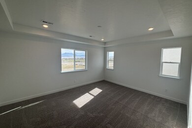 Empty room with a tray ceiling, dark colored carpet, and recessed lighting