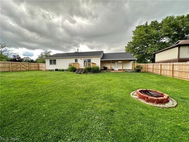 View of yard featuring a fire pit, deck and covered patio fully fenced
