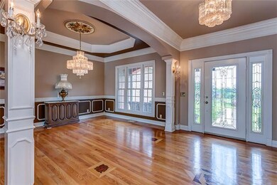 Dining Room features a tray ceiling, Schonbeck crystal chandelier, and wainscoting.