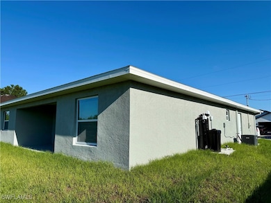 View of side of home with stucco siding and a yard
