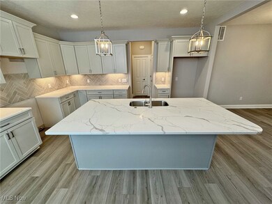 Kitchen with quartz countertops, tasteful backsplash, decorative light fixtures, LVP flooring, and recessed lighting
