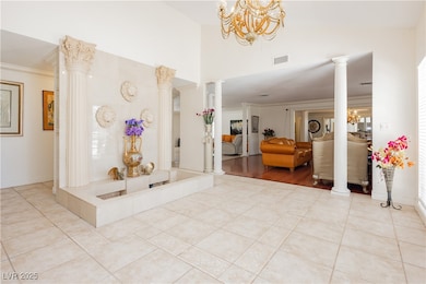 Tiled entryway featuring a chandelier, crown moldi