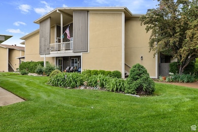 View of property exterior featuring a yard, stucco siding, and a balcony