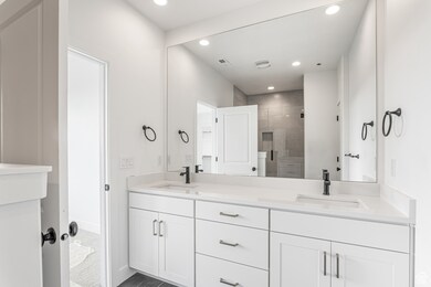 Bathroom with a stall shower, double vanity, and recessed lighting
