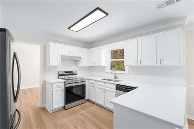 Kitchen with white cabinets, stainless steel appliances, backsplash, and ornamental molding