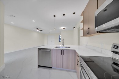 Kitchen featuring appliances with stainless steel finishes, light stone counters, light marble finish floors, modern cabinets, and recessed lighting