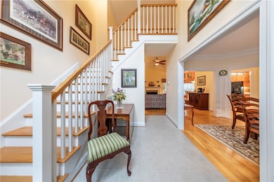 Staircase featuring tile patterned floors, a fireplace, a towering ceiling, and crown molding