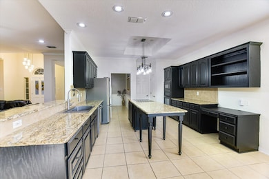 Kitchen with a chandelier, dark cabinets, ornamental molding, backsplash, and light tile patterned flooring