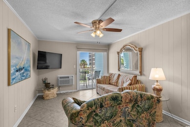 Living room featuring ornamental molding, tile patterned floors, ceiling fan, an AC wall unit, and wood walls
