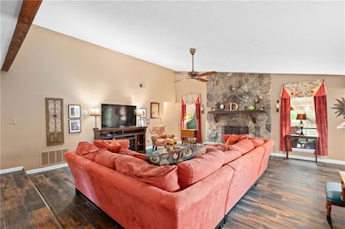 Living room featuring vaulted ceiling, a fireplace, dark wood-style flooring, and ceiling fan