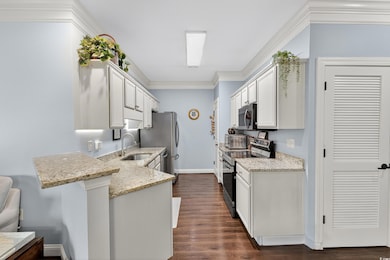 Kitchen featuring ornamental molding, electric range, light stone counters, white cabinetry, and dark wood-style flooring
