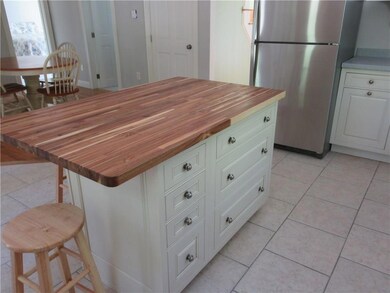 Kitchen island has acacia wood...
