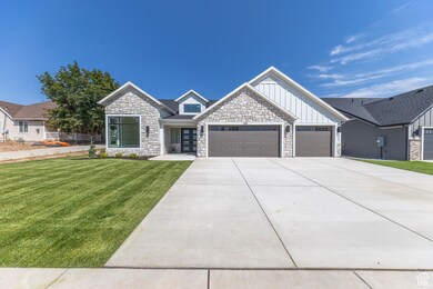 View of front of house with board and batten siding, stone siding, a front yard, a garage, and concrete driveway