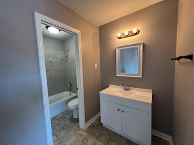 Full bathroom featuring a textured ceiling, tiled 