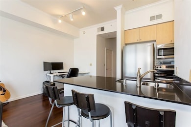 Kitchen with light brown cabinets, stainless steel appliances, a desk, dark wood-style floors, and track lighting