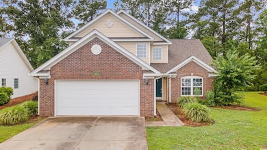 Traditional-style home with brick siding, concrete driveway, a front yard, and roof with shingles