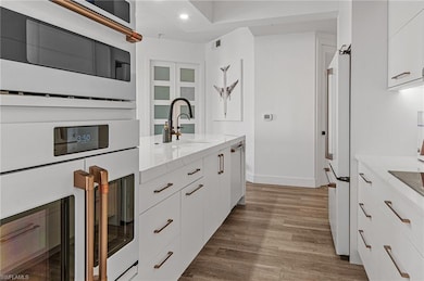 Kitchen with white appliances, light stone counter