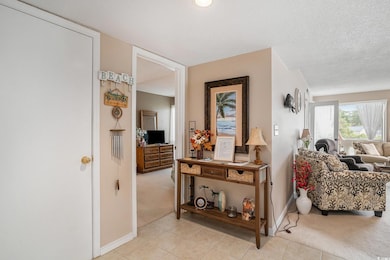 Corridor with light colored carpet, light tile patterned flooring, and a textured ceiling