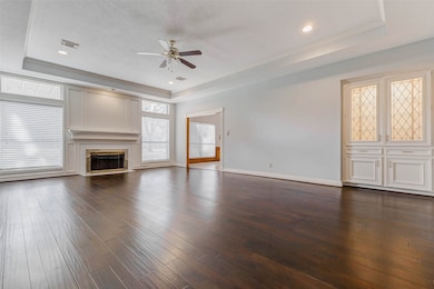 A large, inviting family room anchors the main level, featuring rich wood floors, tray ceiling detail, and a fireplace that serves as the focal point.