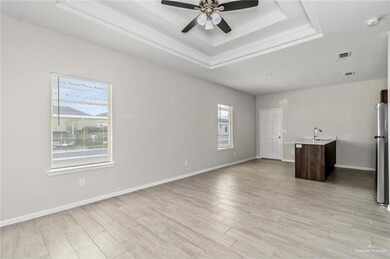 Unfurnished living room with a raised ceiling, ceiling fan, and light wood finished floors
