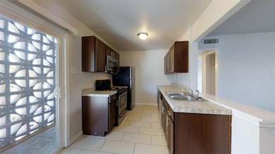 Kitchen with dark brown cabinets, stainless steel appliances, light tile patterned floors, and light countertops