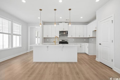 Kitchen featuring appliances with stainless steel finishes, decorative backsplash, light wood finished floors, and recessed lighting
