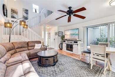 Living area featuring light tile patterned floors, stairs, a ceiling fan, and a towering ceiling