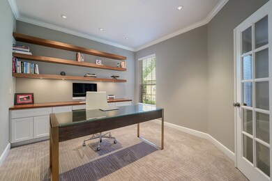 Wonderful home office off front entry features crown molding, added recessed lighting, built-in Kraftmaid cabinets with soft-close feature, custom wood-stained desktop, floating shelves with lighting, plush carpet and front doors for privacy.
