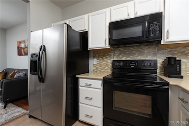 Kitchen featuring black appliances, light countert
