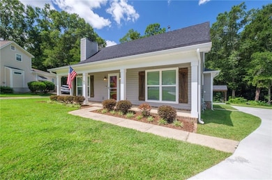 Bungalow featuring a chimney, covered porch, a front yard, and roof with shingles