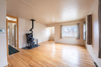 Unfurnished living room featuring light wood-type flooring and a wood stove