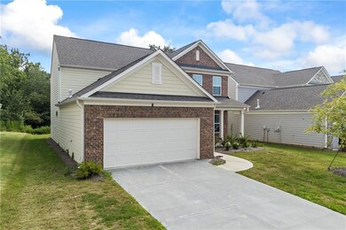 View of front of house featuring brick siding, concrete driveway, a front yard, and a garage
