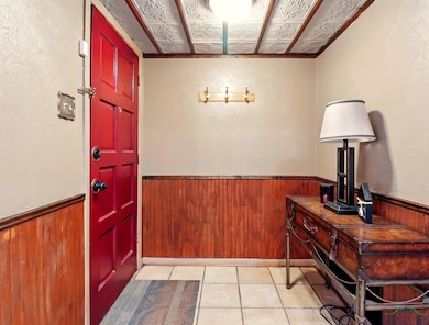 Entryway featuring wood walls, a wainscoted wall, and light tile patterned floors