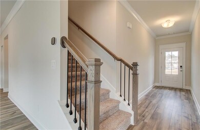 Foyer with wood finished floors, ornamental molding, stairs, and baseboards