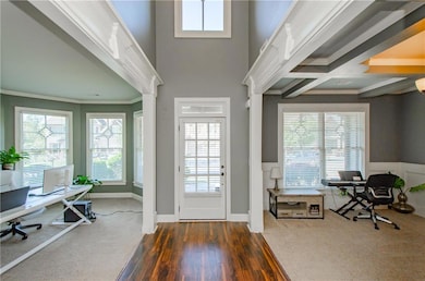 Foyer with ornamental molding, wood finished floors, a wainscoted wall, and beamed ceiling