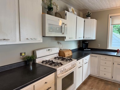 Kitchen featuring white appliances, dark countertops, wood ceiling, dark wood finished floors, and ornamental molding