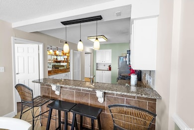 Kitchen with a kitchen breakfast bar, white cabinets, pendant lighting, tasteful backsplash, and a peninsula