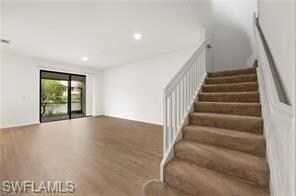 Stairway with wood finished floors and recessed lighting