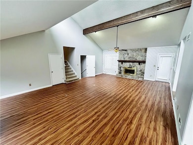 Unfurnished living room featuring a ceiling fan, wood finished floors, a fireplace, and a textured ceiling
