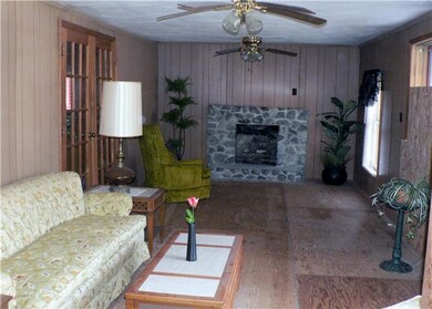 Large den with paneling, double ceiling fans and rock fireplace. Very nice room for entertaining on the holidays. 
