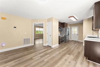 Kitchen featuring appliances with stainless steel finishes, dark brown cabinetry, light countertops, and plenty of natural light