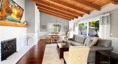 Beautiful Formal Living Room and Dining Room with Vaulted Open Beam Ceiling, Engineered Wood Flooring, Wainscotting on all Walls, Massive White Brick Fireplace with Mantel, and Sliders Leading to Private Gated Front Yard