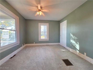 Carpeted spare room featuring baseboards and a ceiling fan