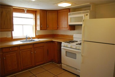 Furnished kitchen has gas stove, refrigerator, built-in microwave.