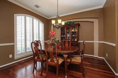 Spacious dining room with beautiful wood floors, plantation shutters, arches and upgraded light fixture.