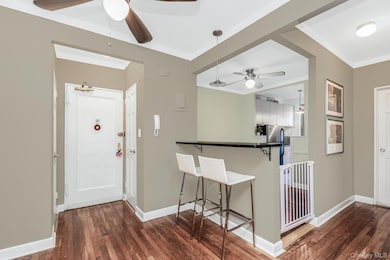 Entryway with ceiling fan, crown molding, dark wood-style floors, and baseboards