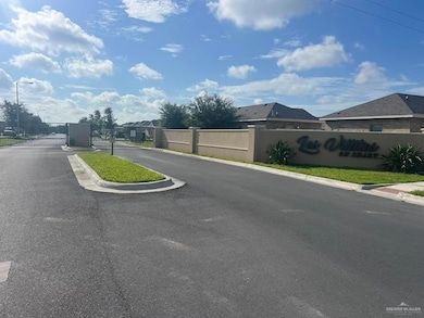 View of asphalt road featuring street lights, a gated entry, a gate, and curbs